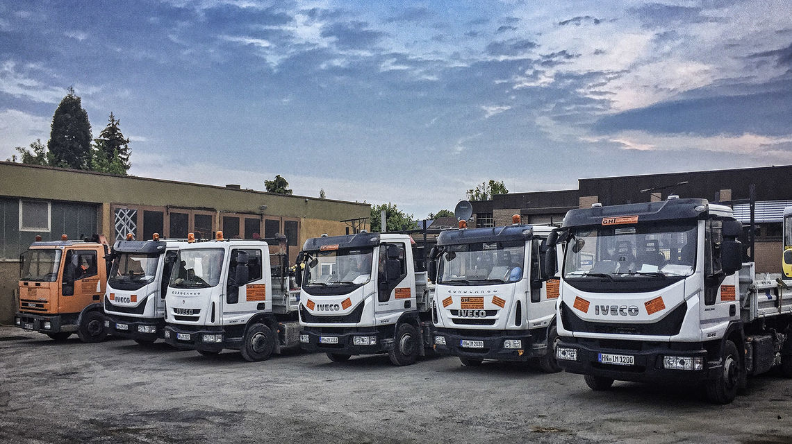 Unser Fuhrpark Ein Bild von mehreren firmeneigenen LKW, die auf dem Firmengelände stehen.